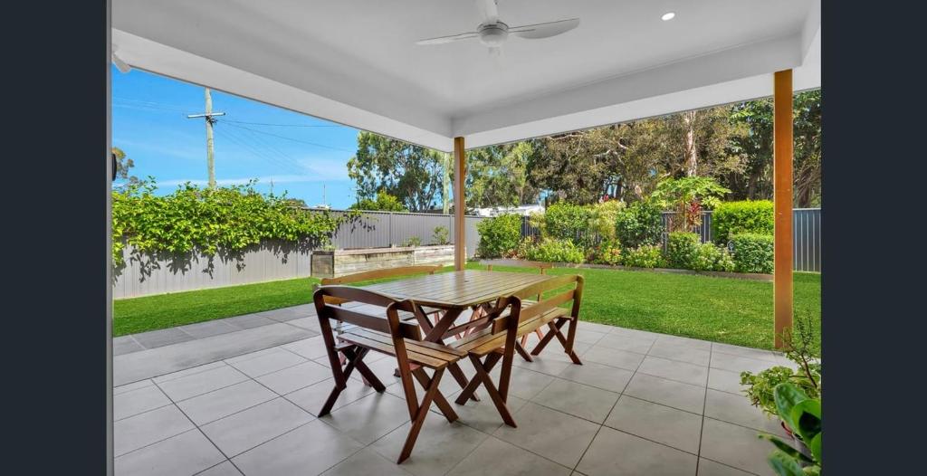 a table and chairs under a white umbrella on a patio at 1 Seaspray Avenue in Coolum Beach