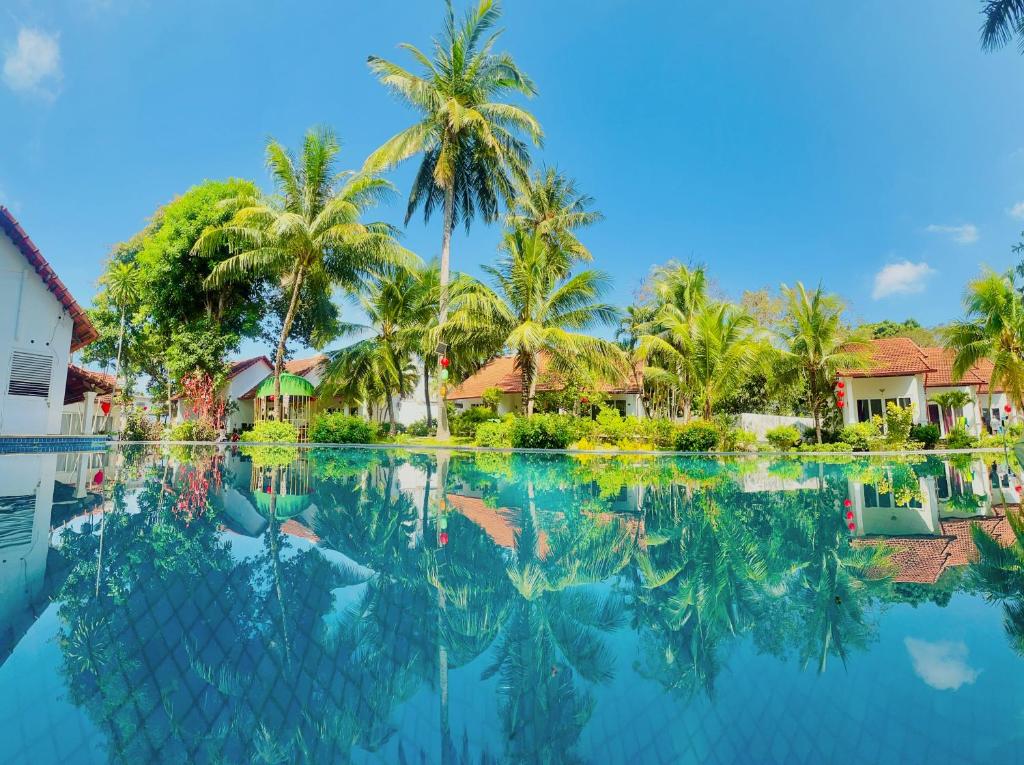 a pool in front of a house with palm trees at Terrace Resort in Phú Quốc