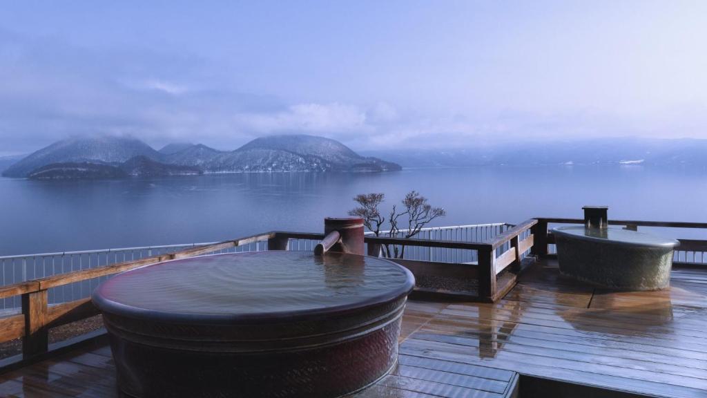 a table on a deck with a view of the water at Toya Kohan Tei in Lake Toya