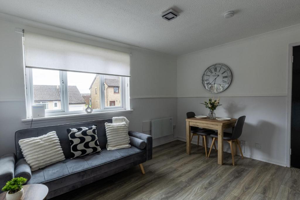 a living room with a couch and a table and a clock at Anderson Apartment in Airdrie