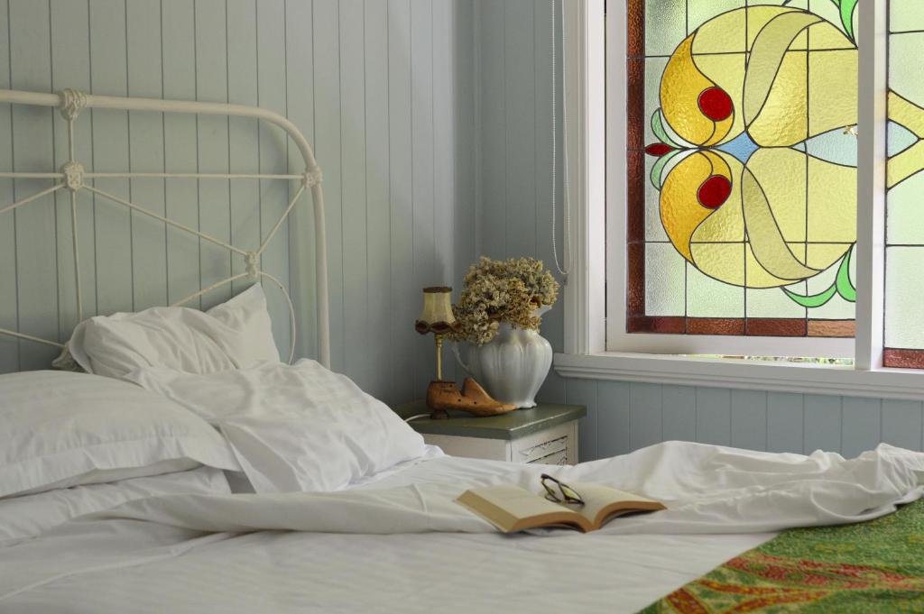 a bed with a book on it with a window at Juniper & Rye cottage for two in Ferny Creek