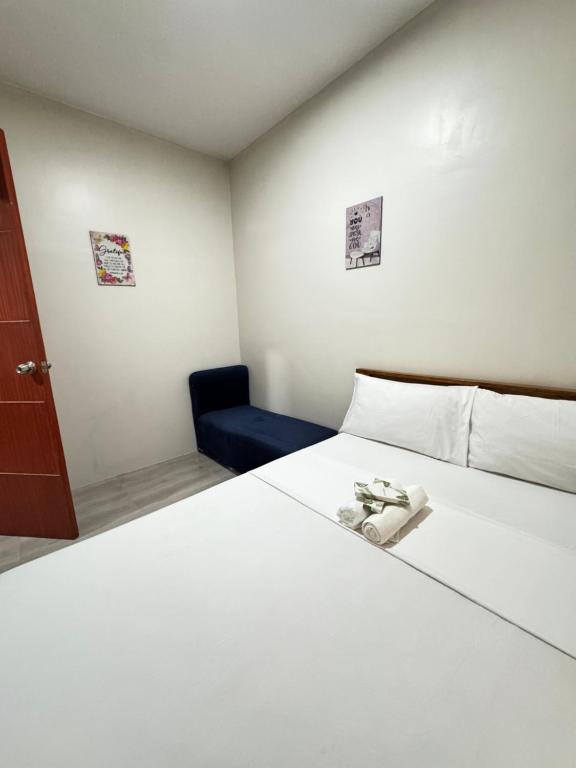 a bedroom with a white bed and a blue chair at Southsea Staycation-couple in Nasugbu