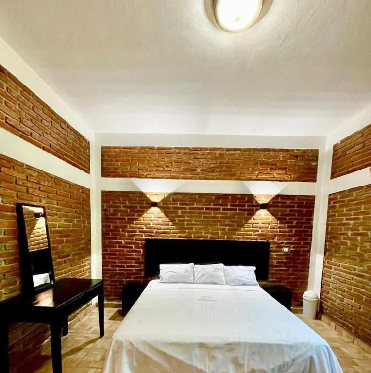 a bedroom with a bed and a brick wall at Hotel sueño pacifico in Entabladero