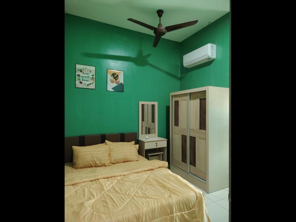 a green bedroom with a bed and a ceiling fan at D 'Fidarez Homestay in Pendang
