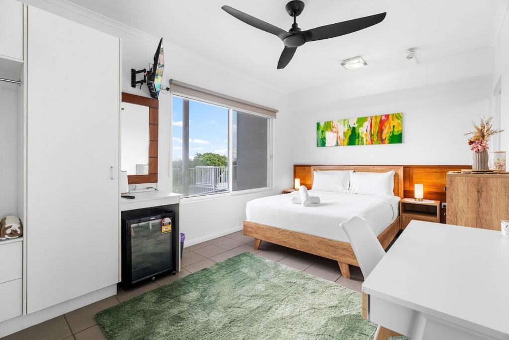 a white bedroom with a bed and a window at Zen Marina Studio: bayview - shared pool - central in Larrakeyah