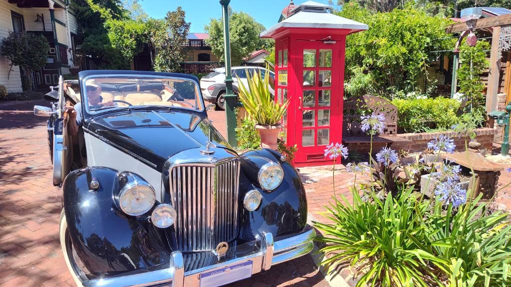 an old blue car parked next to a red phone booth at Bridgefield Guest House in Margaret River Town