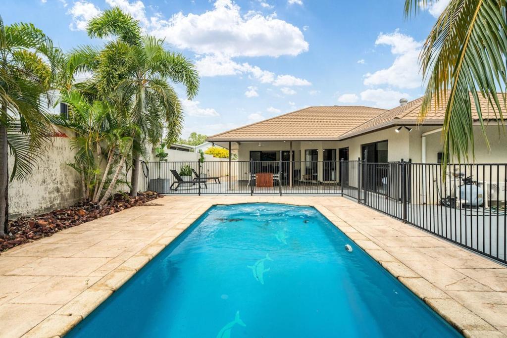 a swimming pool in front of a house with palm trees at Zen Orient Luxurious 4BR Oasis with Private Pool in Leanyer