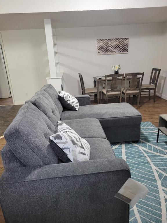 a living room with a gray couch and a dining room at Executive Cozy 2bedroom Basement Suite in Brandon