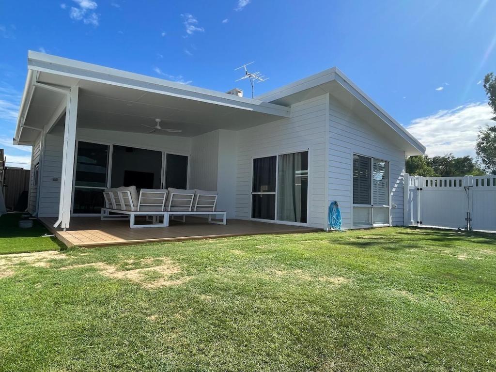 a white house with a bench on a deck at Silver Sands Villa in Mandurah