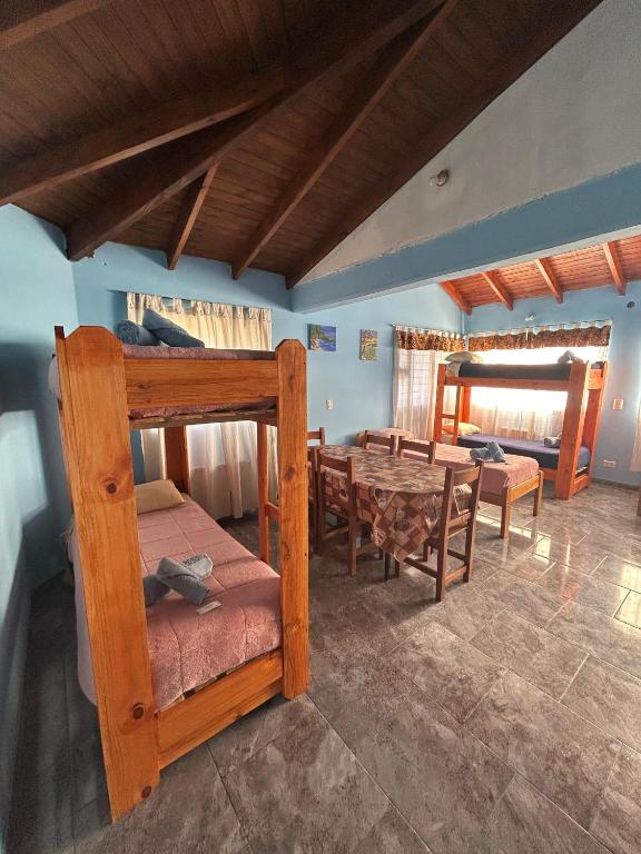 a room with a bunk bed and a table and chairs at Hostel Acuarelas in El Chalten