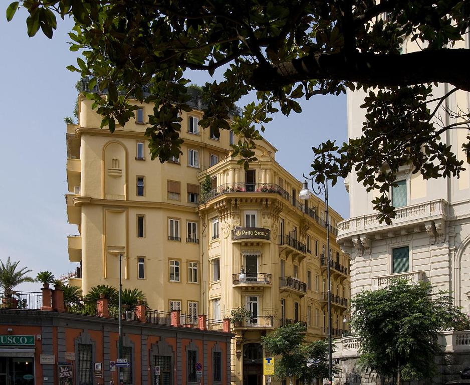 ein großes gelbes Gebäude neben einem weißen Gebäude in der Unterkunft Pinto-Storey Hotel in Neapel