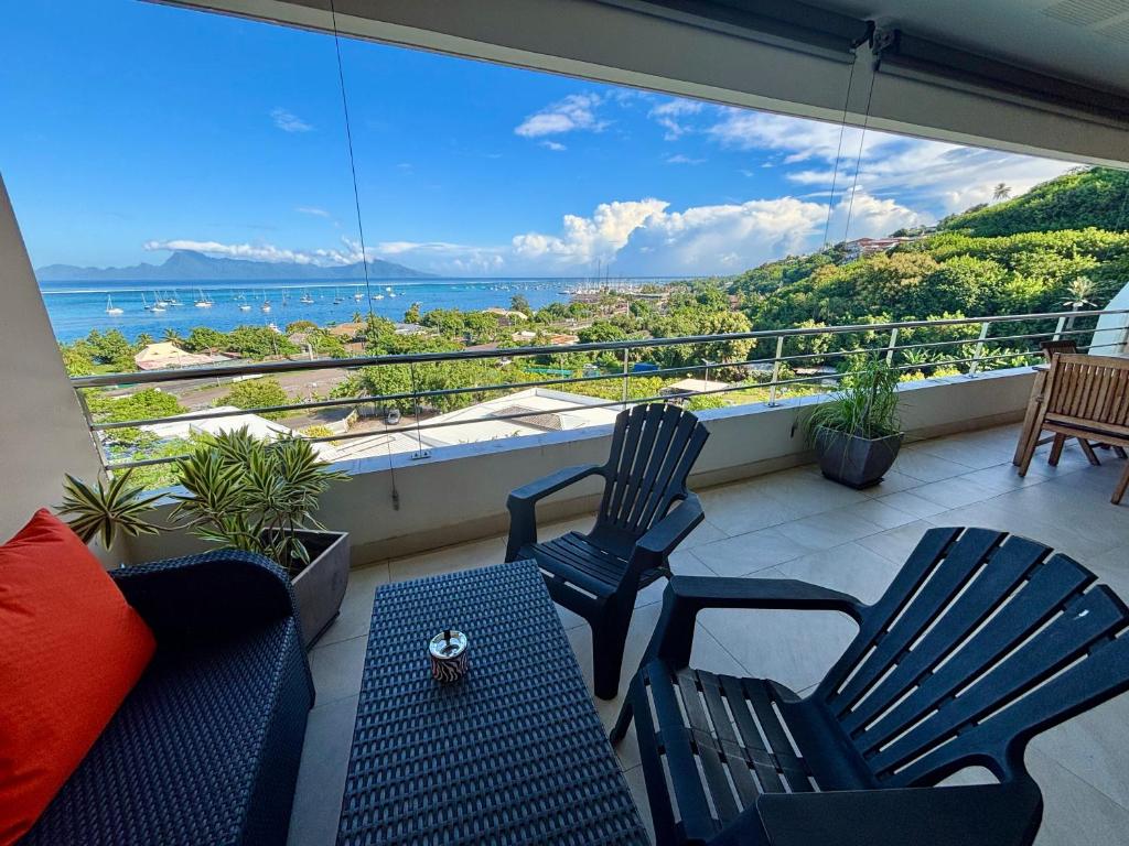 two chairs and a table on a balcony with a view of the ocean at Tahiti Ethnik 2 bedrooms AC Pool in Punaauia