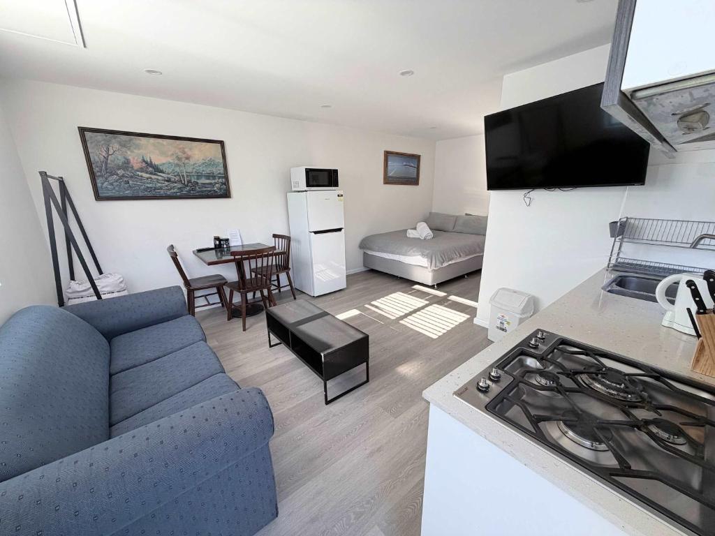 a living room with a blue couch and a kitchen at Claremont Comfort Cottage in Claremont