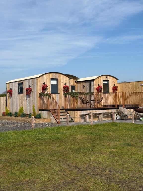 a row of wooden buildings with flowers on them at The Shepherds Chalet in Garstang