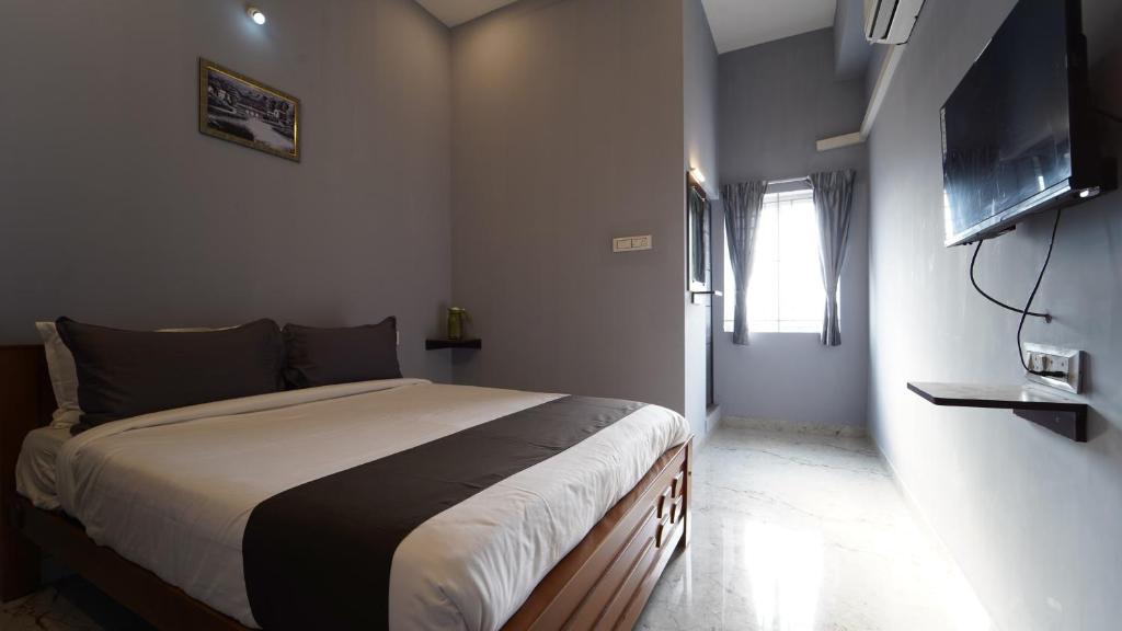 a bedroom with a bed and a flat screen tv at MM Hotel Grey Luxury in Coimbatore