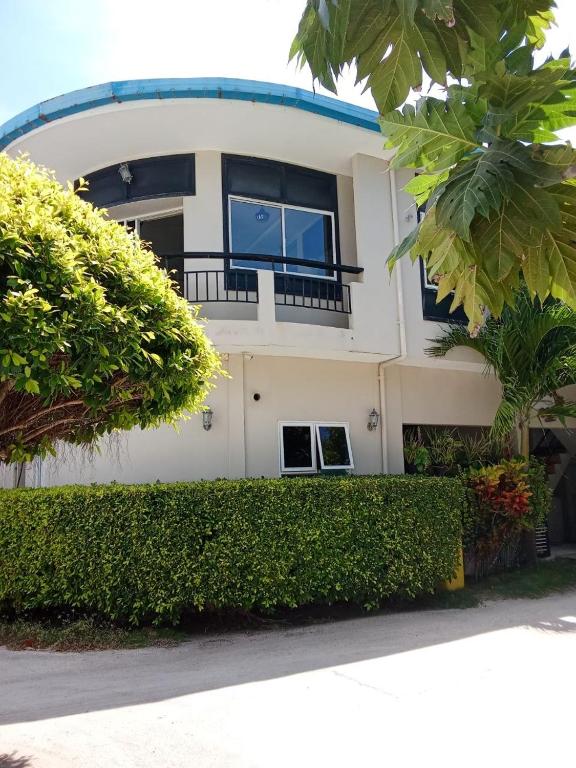a white house with a large window and bushes at Seaside Villa in Dhiffushi