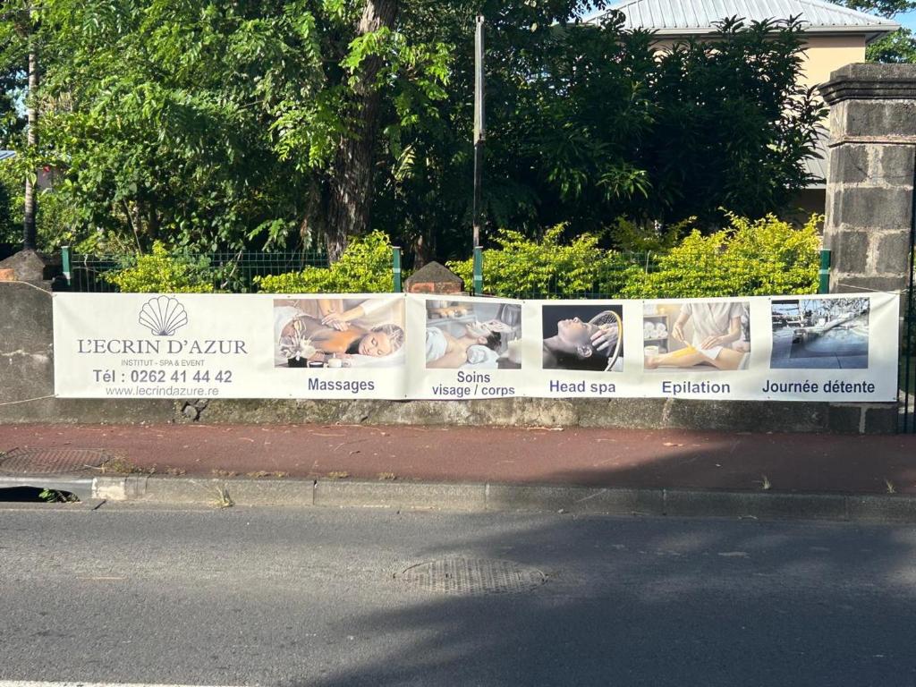 a fence with pictures of babies on the side of a street at L' ecrin de douceur in Saint-Benoît