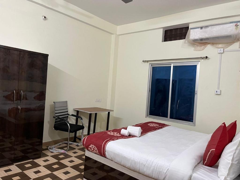 a bedroom with a bed and a window and a chair at Hotel PSR INN in Mughal Sarāi