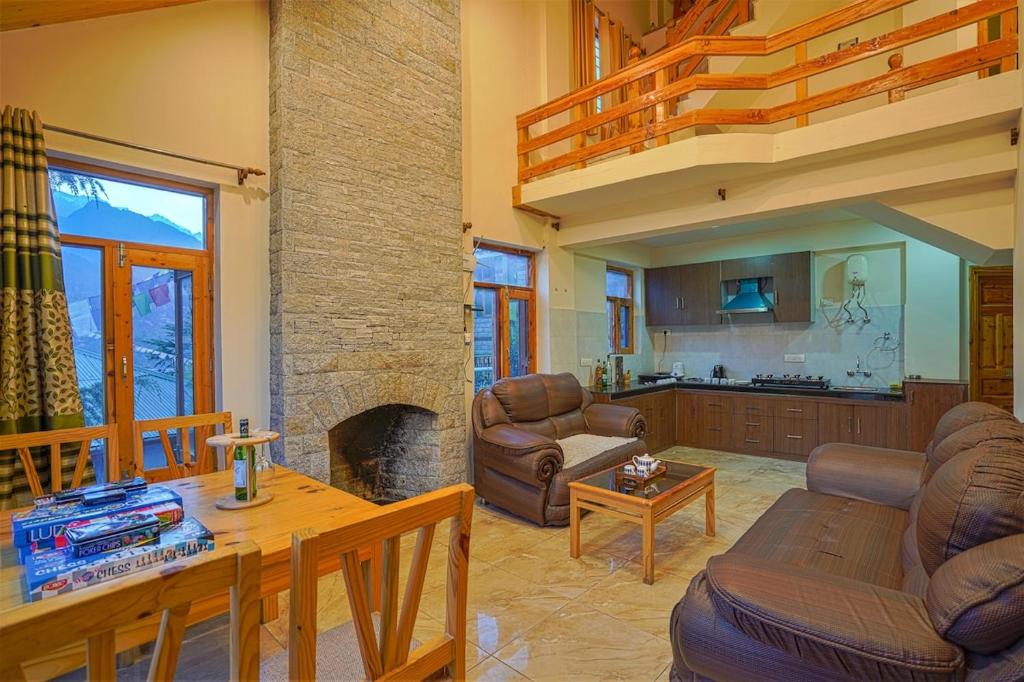 a living room with a couch and a fireplace at Pine Wood Chalet in Manāli