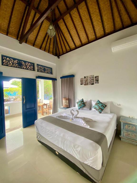 a bedroom with a large bed and a blue door at Inti Bungalows in Gili Trawangan
