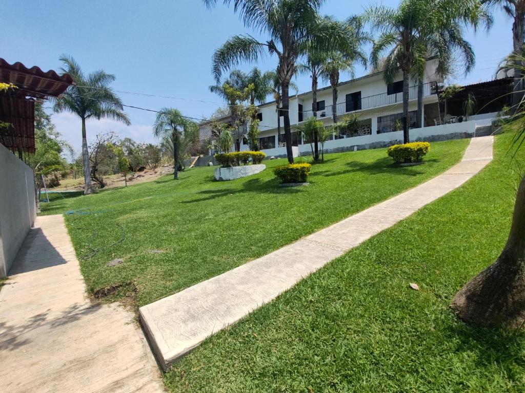 a walkway through a park with palm trees and a building at La gloria hospedajes in Cuernavaca