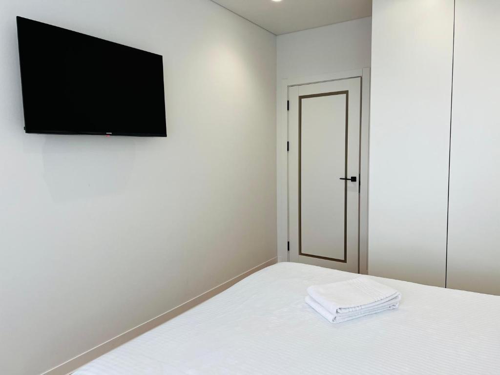 a bedroom with a bed and a tv on a wall at Apartament white Arena in Chişinău