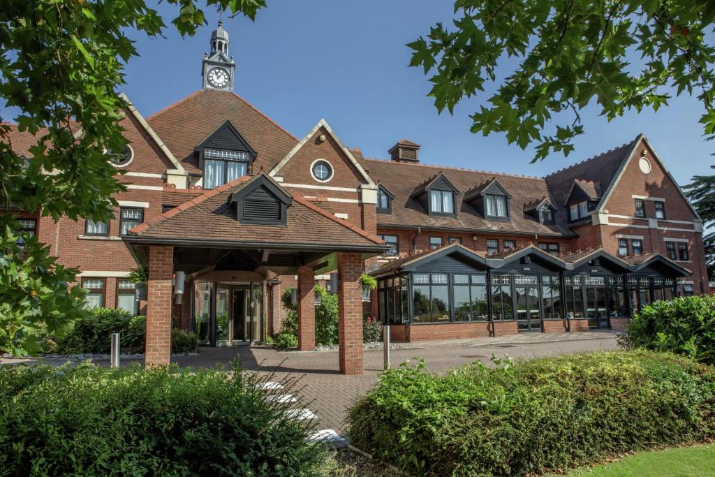 a large brick building with a clock tower on top at DoubleTree by Hilton Stratford-upon-Avon, United Kingdom in Stratford-upon-Avon