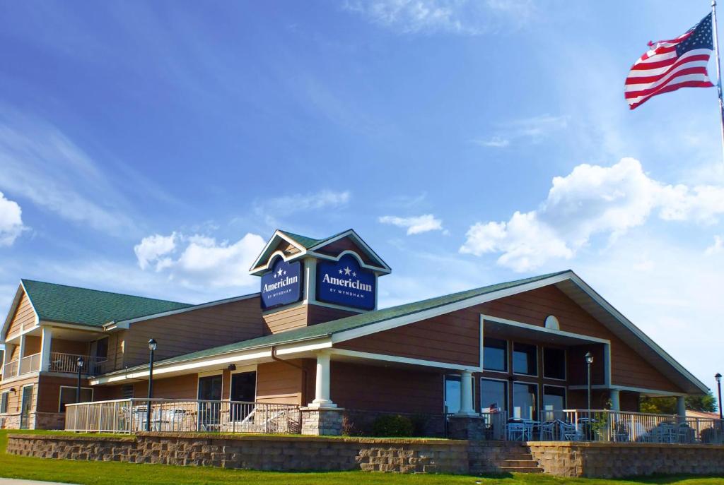 a building with an american flag in front of it at AmericInn by Wyndham Okoboji in Okoboji