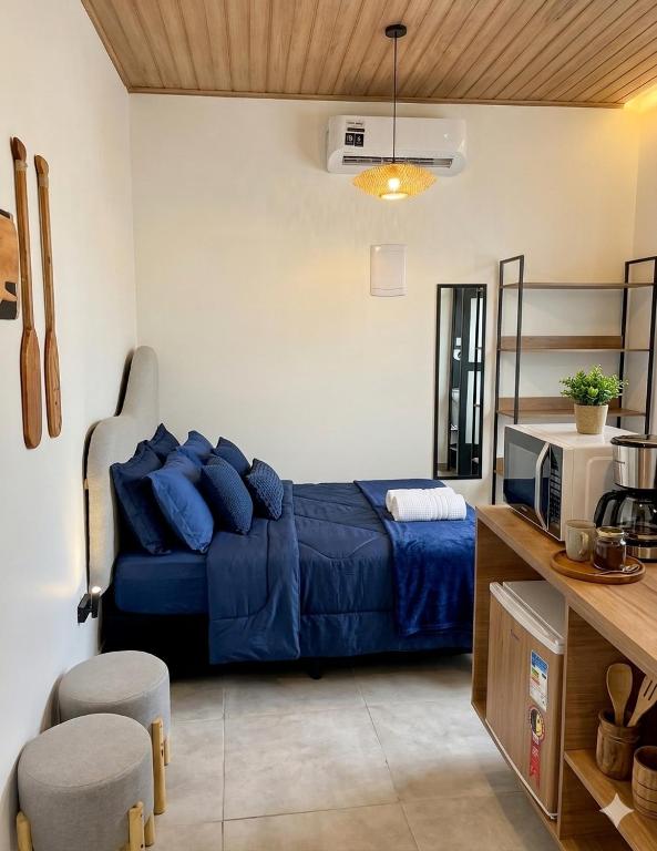 a bedroom with a bed with blue pillows in it at Onda Studios Apê Completo - Vista Linda e Sesc Bertioga - Ar Condicionado in Bertioga