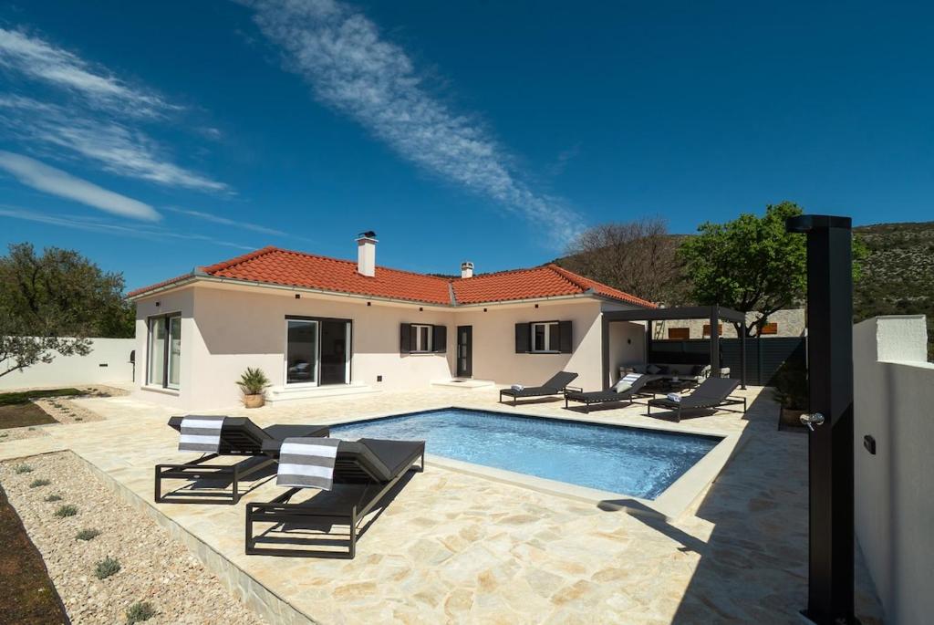 a swimming pool with lounge chairs and a house at Casa Mia in Danilo Biranj