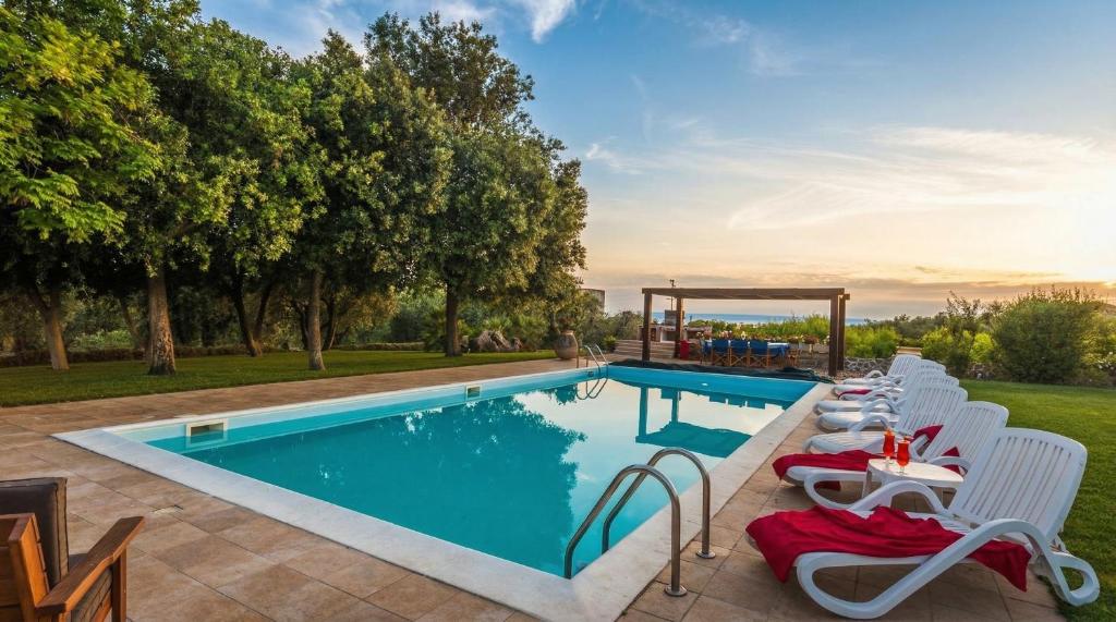 an outdoor swimming pool with chairs and a table and a swimming pool at ClickSardegna Villa Emanuel spectacular sea view, with independent swimming pool in Alghero