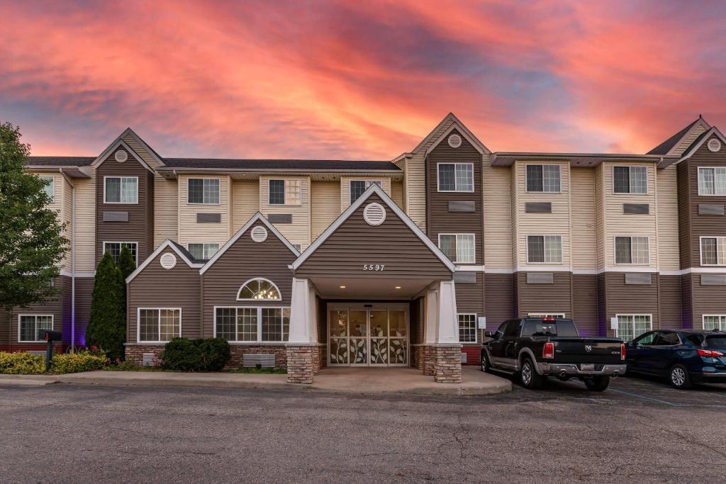 a building with a car parked in a parking lot at Sleep Inn & Suites Kalamazoo Southwest in Kalamazoo