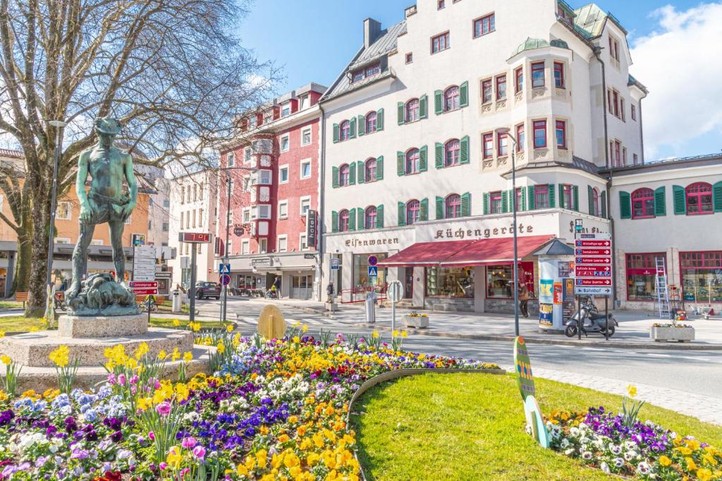 a city street with a statue and flowers at Hotel Kufsteinerhof in Kufstein
