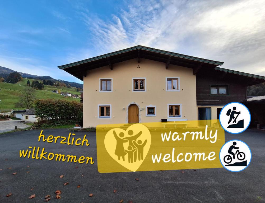 a house with a welcome sign in front of it at Haus Thussn, Ferienwohnung für Familien und Paare in Kirchberg in Tirol