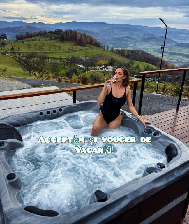 a woman in a bathing suit sitting in a hot tub at Cabana Bradova Jacuzzi & Heated Pool A-Frame in Bîrsana