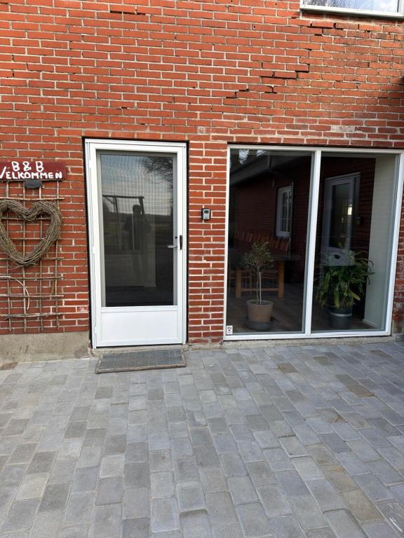 a white door on a brick building with windows at Højmosegård værelse 1 in Varde