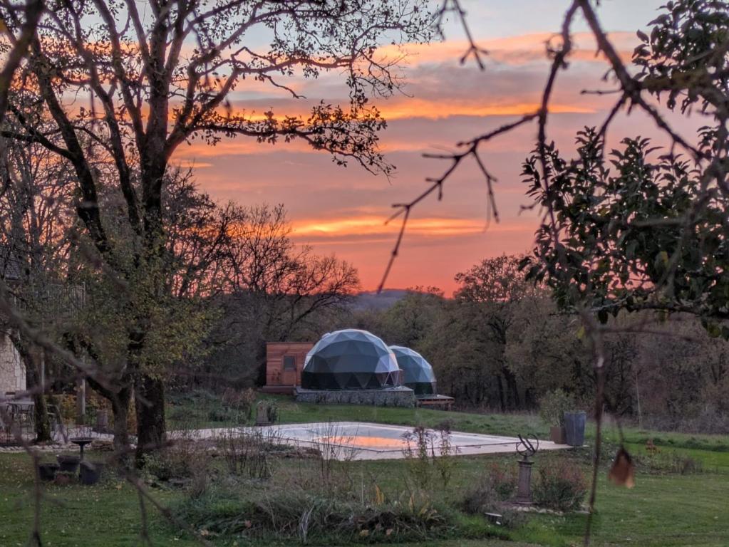 a tent in a field with a sunset in the background at Glamping Dôme Benzène in Fonmourenne