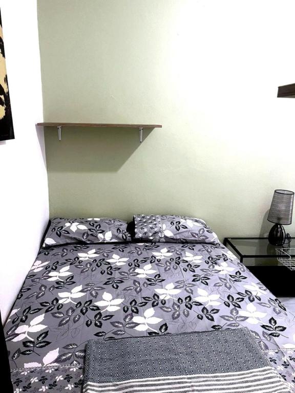 a bed with a black and white comforter in a bedroom at Cocon lumineux tout équipé in Dzaoudzi