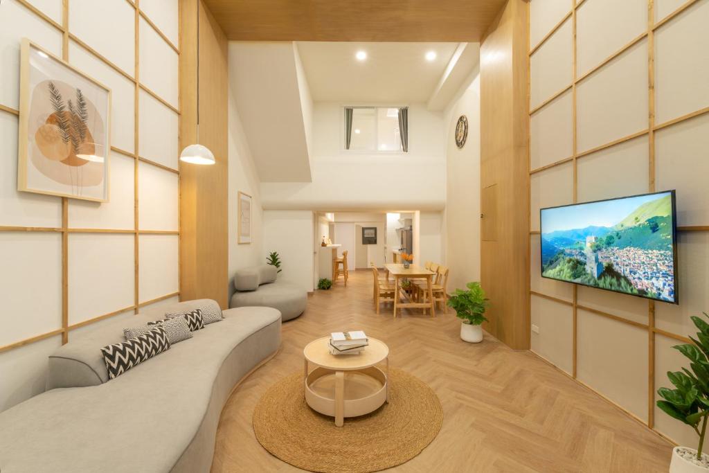 a living room with a couch and a tv on a wall at Tungyu Home Old Town - 1 min to walking street in Chiang Mai