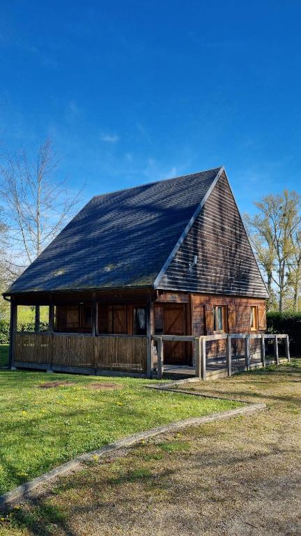 a large wooden barn with a black roof at Les Chalets de la Besbre in Jaligny
