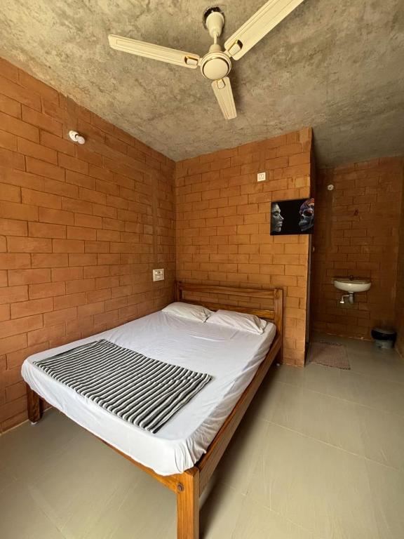 a bed in a room with a ceiling fan at Auro Waves Rooms & Hostel in Auroville