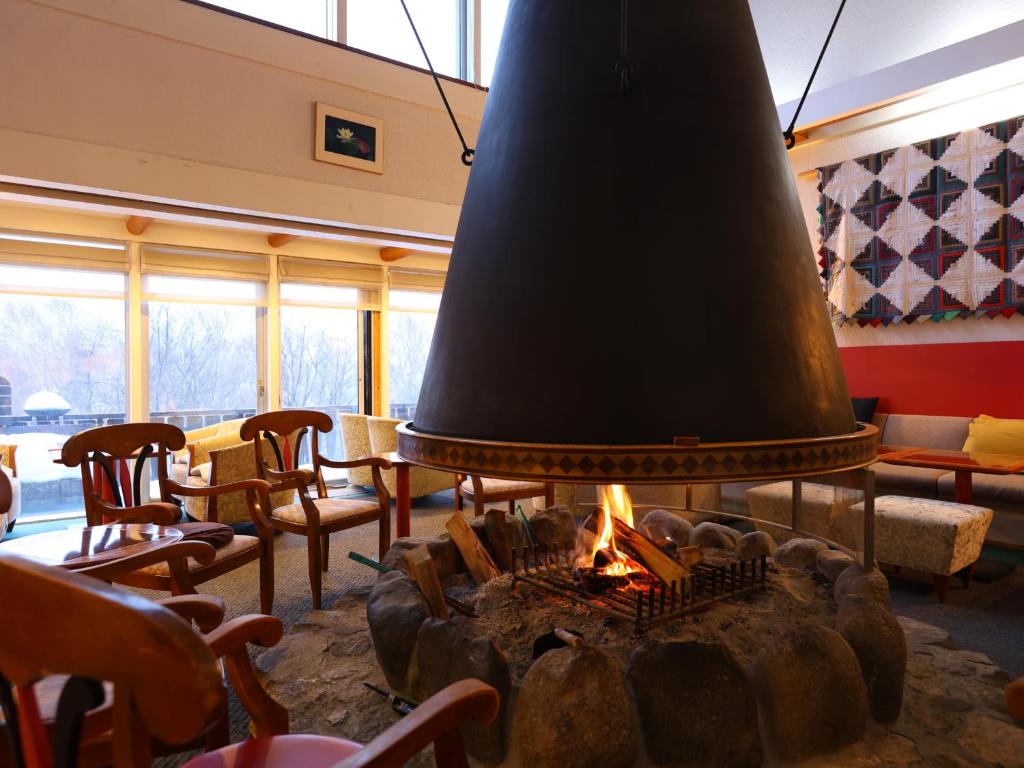 a fireplace in a room with chairs and a large bell at Hotel Takimoto in Yamanouchi