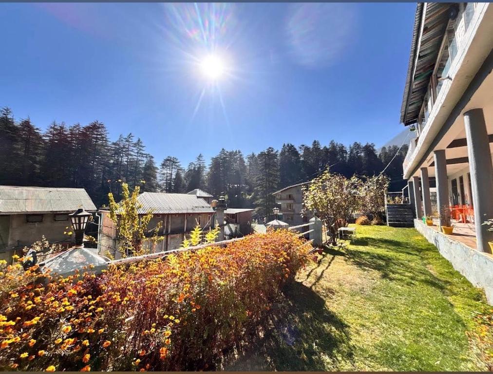 a view of a yard with flowers and a house at Green forest BnB and cafe in Manāli