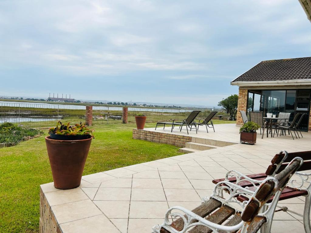 a patio with chairs and a view of the water at River Front Guest House in Gqeberha