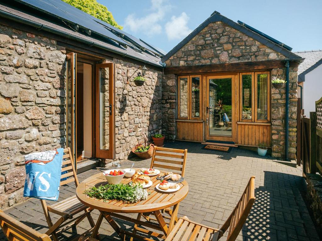 a patio with a table and chairs and a house at Cob Cottage in Rhossili