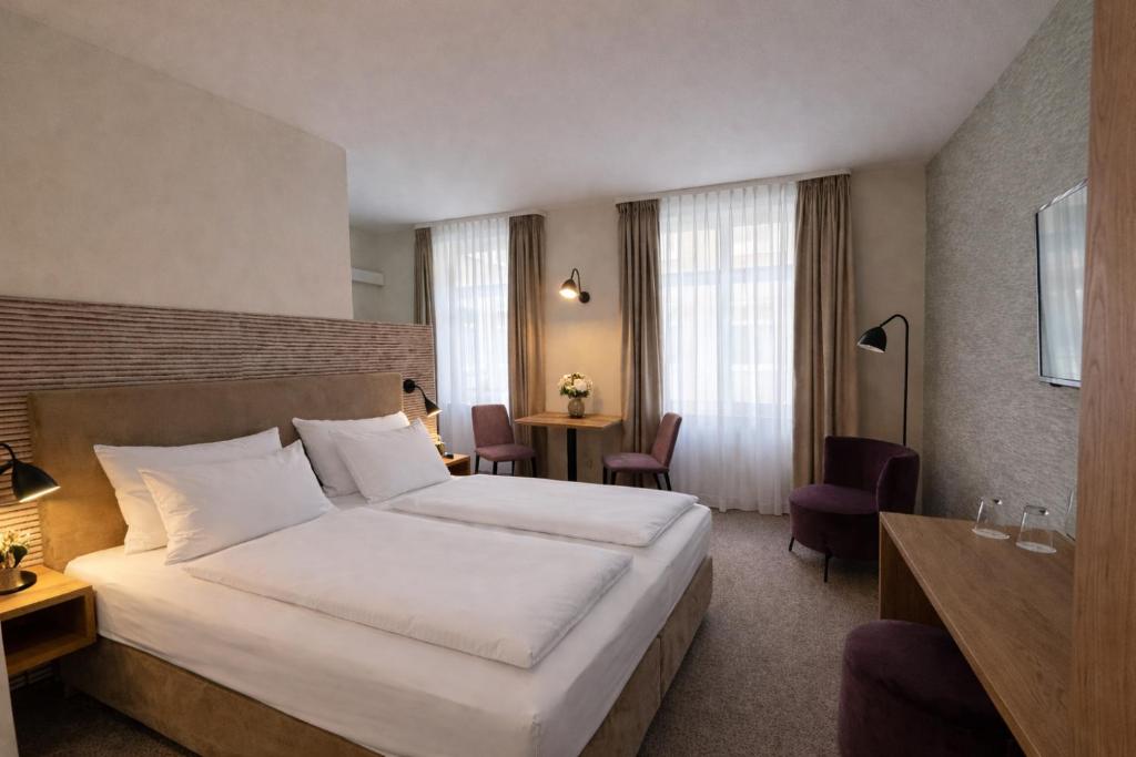 a hotel room with a large bed and a table at DORMERO Aparthotel Stralsund in Stralsund