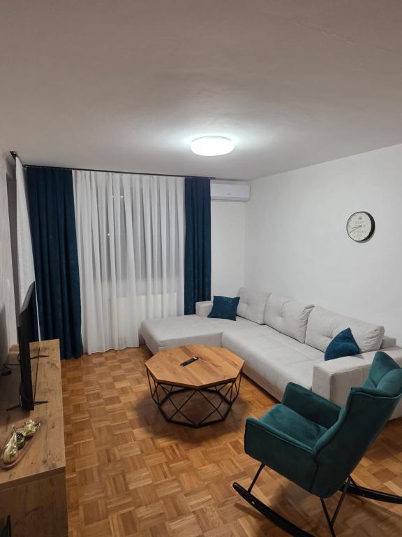 a living room with a white couch and a table at Apartman Anja'K in Doboj