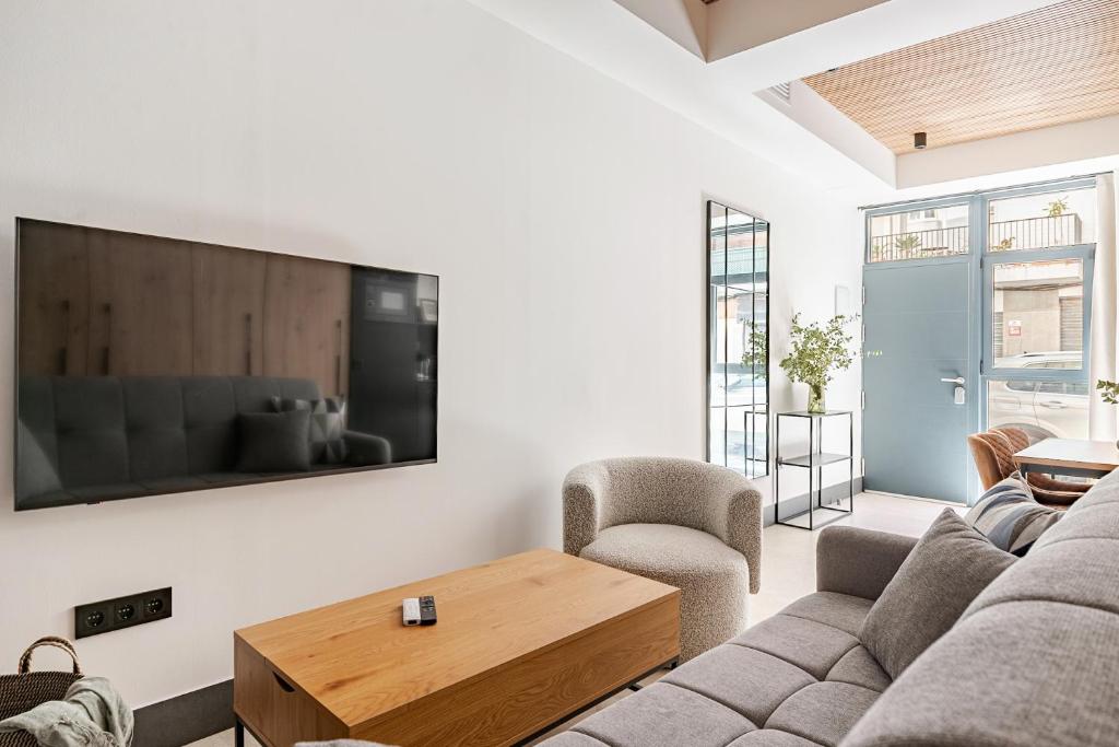 a living room with a couch and a tv on a wall at Elcano Suites in Seville