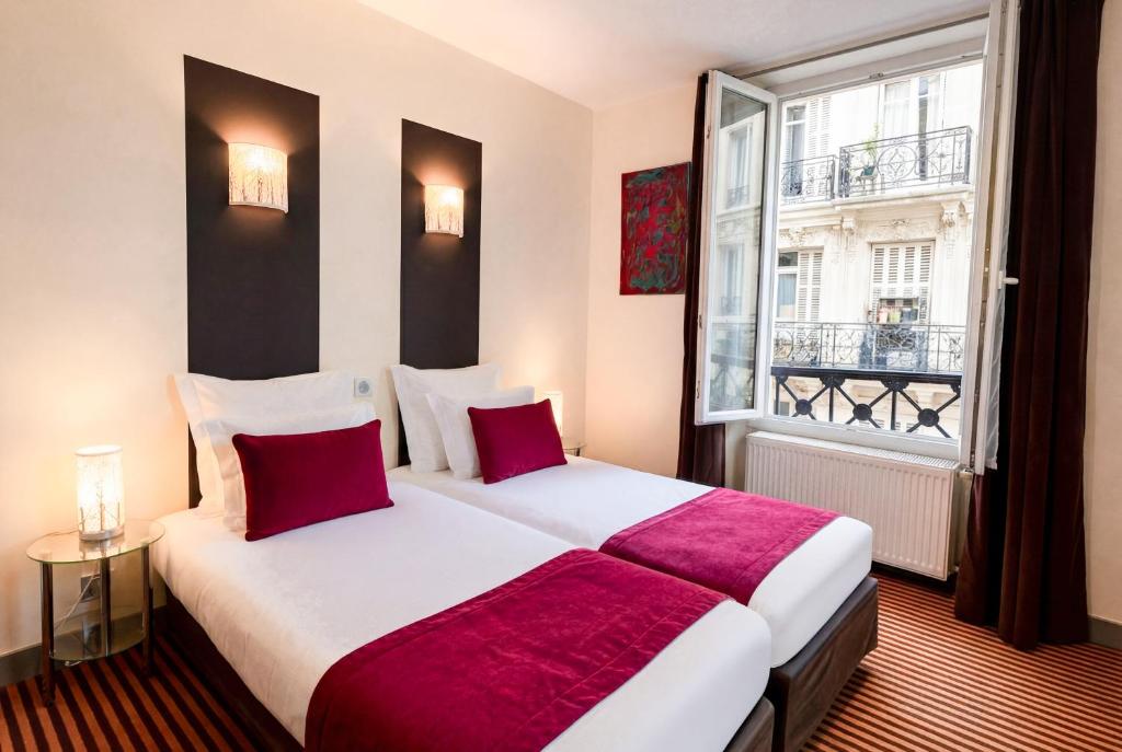 a hotel room with two beds and a window at Hotel Pax Opera in Paris