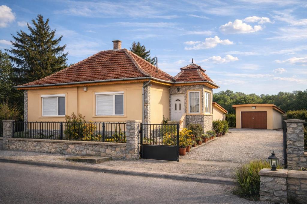 a house with a fence and a driveway at Törpi Apartman in Halmaj
